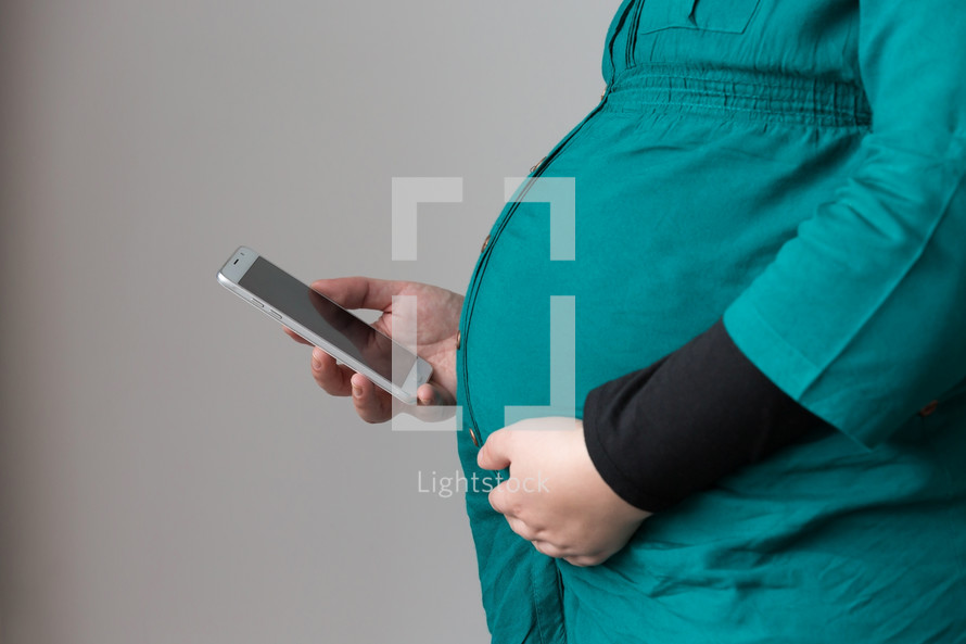 a pregnant woman reading a Bible app on her phone 