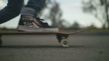 Skater places his foot on a skateboard and then rides away