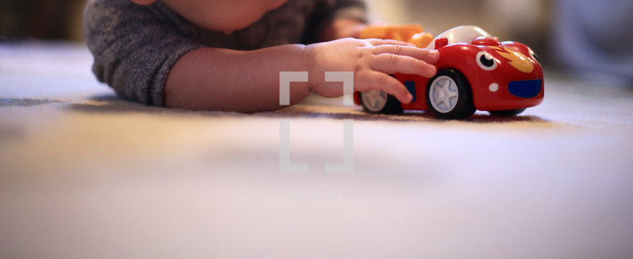 an infant playing with a toy car 