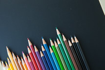 row of colored pencils on a black background 