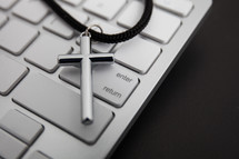 silver cross on a lanyard on a computer keyboard 