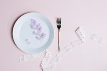 Sweet healthy concept with fork, white ribbon over the pink background.