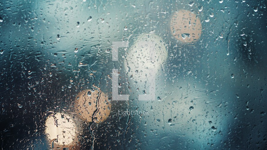 Close up view of water drops falling on glass. Rain running down on window. Rainy season, autumn. Raindrops trickle down, bokeh sky