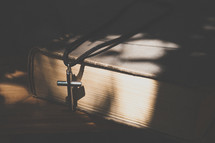 silver cross on a Bible in sunlight 