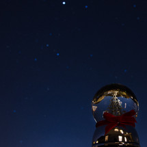 christmas tree in a snow globe and stars in the night sky
