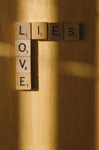 Scrabble tiles arranged to show how love is in the light and lies lead to shadows.