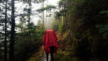 man in a poncho standing in a forest 