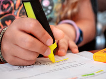 a girl uses a highlighter while doing school homework