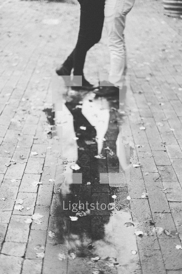 reflection of a couple hugging in a puddle on patio brick 