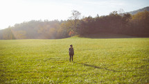 a woman standing alone in a meadow 