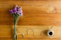 bouquet of purple flowers and twine on a wood background 