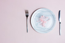 Sweet diet concept with marble plate, knife and fork over the pink background. 