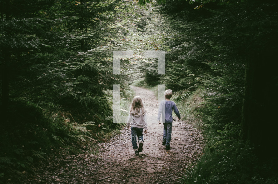 a boy and girl on a forest path
