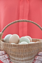 hands holding a basket full of eggs