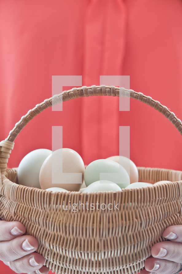 hands holding a basket full of eggs