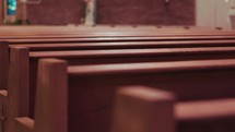 Slow-motion dramatic shot of empty wooden church pews.