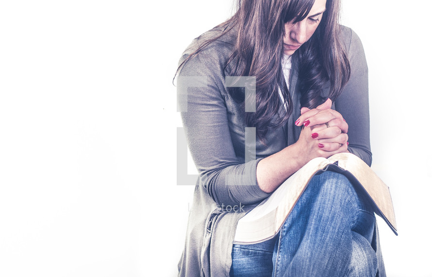a woman praying with a Bible in her lap 