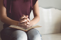 a teen girl praying over a Bible 