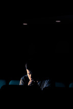 man sitting in an empty auditorium with his head bowed in prayer