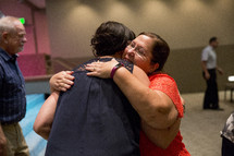 two women hugging during a worship service 