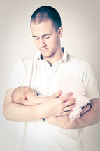 father cradling a newborn