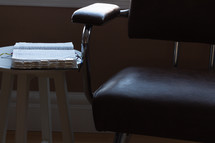 a Bible on a stool next to a chair 