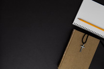 cross necklace, pencil, notebook, and Bible 