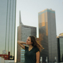 a woman standing in a city with skyscrapers behind her 