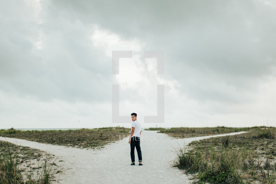 a young man walking over sand dunes 