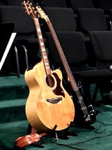 An acoustic and electric set of guitars and stand on a church stage in preparation for a contemporary worship music on a Sunday morning praise band concert.  