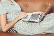 a woman lying on a couch with her laptop 
