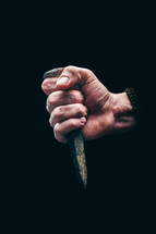 hand grasping a nail spike 