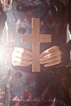 woman in a peacoat holding a cardboard cross