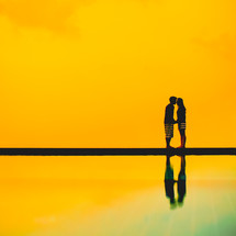 a couple holding hands with the golden sky as a backdrop 