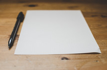 a pen and blank sheet of paper on a desk
