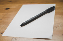 A blank piece of paper and pen on a writing desk