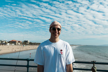 a man in a beanie standing on a pier 