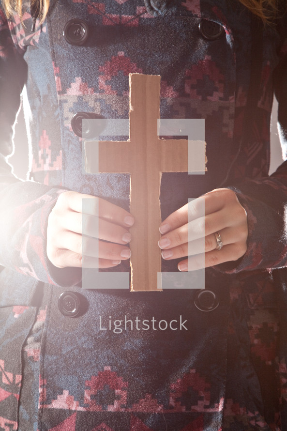 woman in a peacoat holding a cardboard cross