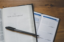 A bible opened at the new testament with a 2017 diary planner open on a desk