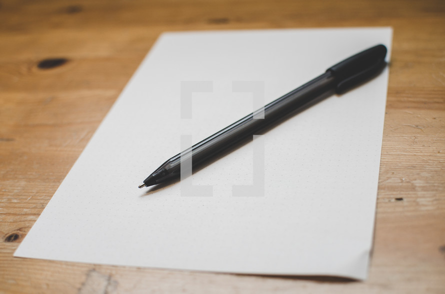 A blank piece of paper and pen on a writing desk