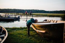 toddler exploring boats along a shore 