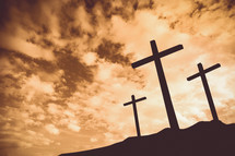 silhouettes of three crosses on a hill 