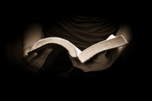 torso of a man reading a Bible 