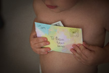 A young child holding a letter from his mother.