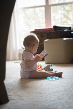 infant sitting on the floor playing with toys 