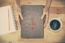 a man sitting at a table and a wooden cross on a Bible 