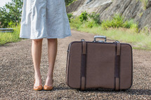 woman legs standing next to luggage 