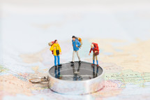 miniature figurines standing on a map and compass