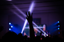 silhouette of a raised hands and spotlights at a concert 
