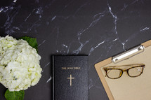 Bible on a black marble desk with white flowers 